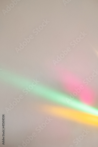 Neon light background. Rainbow color. Disco party. Festive art surface. Colorful pink yellow green blur glowing rays overlay on neutral wall.