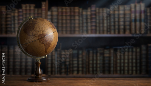 Old geographic globe in the cabinet against the background of bookselfs.Science, education, travel, vintage background. History and geography team.