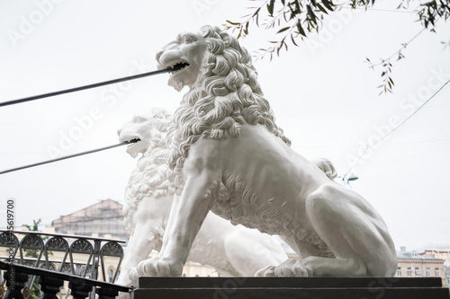 Saint-Petersburg, Russia, 28 August 2020: Side view of sculptures of lions on background of cloudy sky. Pedestrian bridge of Four Lions over the Griboedov Canal. photo