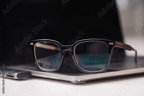 Closeup black eyeglasses and laptop on desk, learning concept.