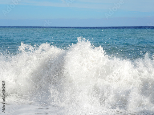 Big wave with sea foam and blue water. Beach Splashing Waves. Summer background. Foam of the sea. 