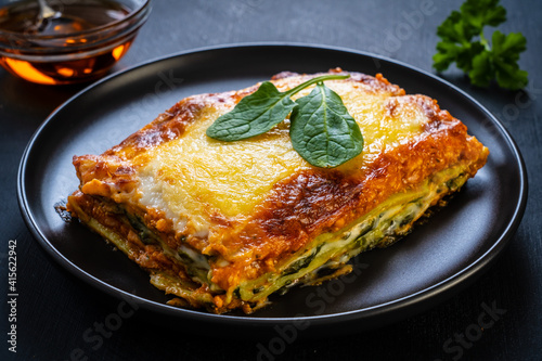 Lasagna with pork and spinach on black table 