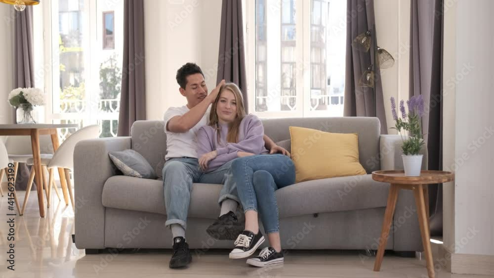 Portrait of young couple smiling and looking at the camera while sitting on the couch at home. Portrait of young couple smiling and looking at the camera while sitting on the couch at home.