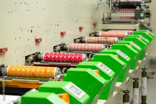 Flexography printing process on in-line press machine. Photopolymer plate stuck on printing cylinder, substrate is sandwiched between plate and impression cylinder to transfer ink. Label manufacturing