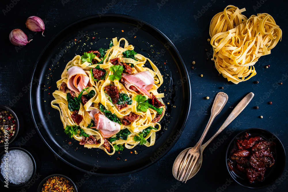 Carta da parati Tagliatelle with bacon, sun-dried tomatoes and spinach in alfredo sauce on black