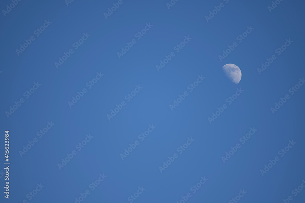 Closeup shot of the Moon in the blue clear sky - perfect for background Closeup shot of the Moon in the blue clear sky - perfect for background