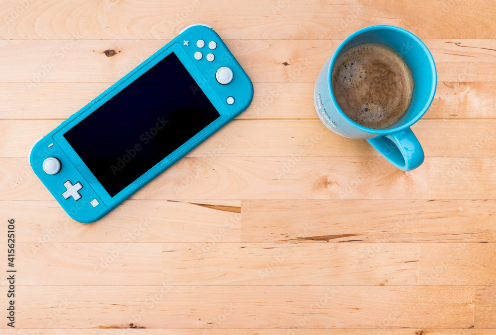 Video game console blue Nintendo Switch on wooden table - top view - white  blank screen - breakfast scene with cup of coffee - high resolution photo  Stock-Foto | Adobe Stock