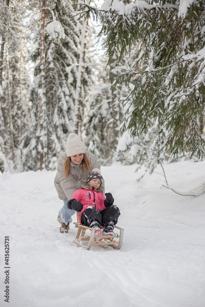 Mother with daughter have fun in winter forest, riding on sledge and laughing. Mother with daughter have fun in winter forest, riding on sledge and laughing.