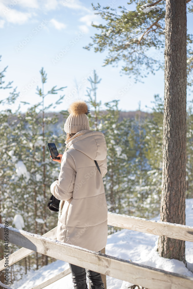 Fototapeta premium Young woman take a photo with mobile phone in snowy forest.
