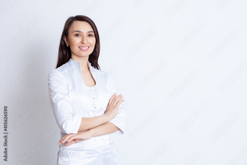 A young beautiful doctor girl in a white robe with dark hair. Portrait on a white background A young beautiful doctor girl in a white robe with dark hair. Portrait on a white background