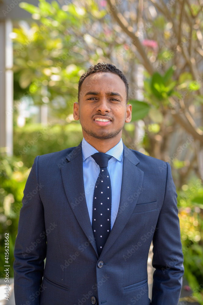 African businessman wearing suit and smiling outdoors vertical shot African businessman wearing suit and smiling outdoors vertical shot
