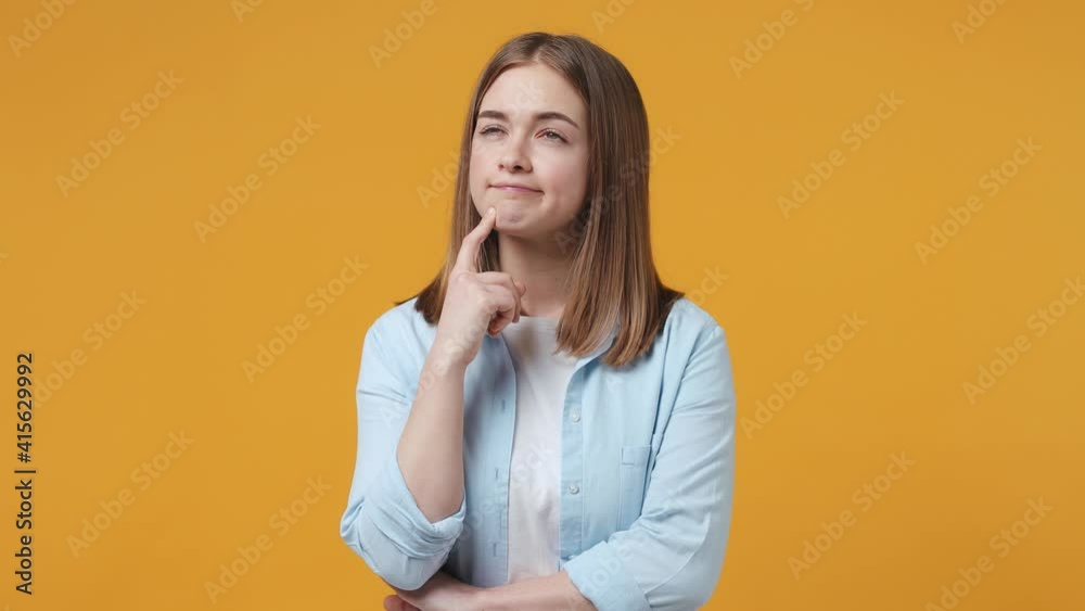 Preoccupied excited blonde young woman 20s years old in blue shirt posing isolated on yellow background studio. People sincere emotions lifestyle concept. Holding index finger up with great new idea Preoccupied excited blonde young woman 20s years old in blue shirt posing isolated on yellow background studio. People sincere emotions lifestyle concept. Holding index finger up with great new idea
