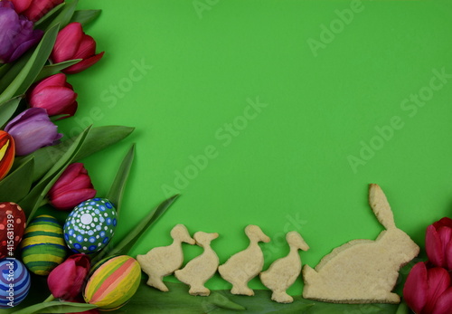 tulips, painted eggs, bunny- and chickshaped cookies on green background photo