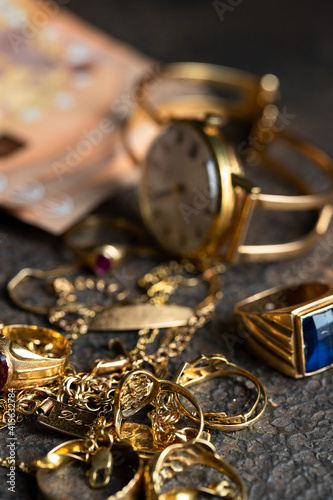 Old and broken jewelry  and on Euro banknotes on dark background. Sell gold for money  concept.