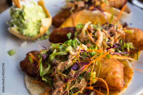 Battered fish tacos topped with slaw and salsa, served with guacamole at a restaurant on the beach of Bucerias, Mexico