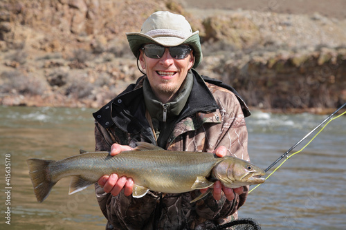 adult fisherman holding steelhead trout
