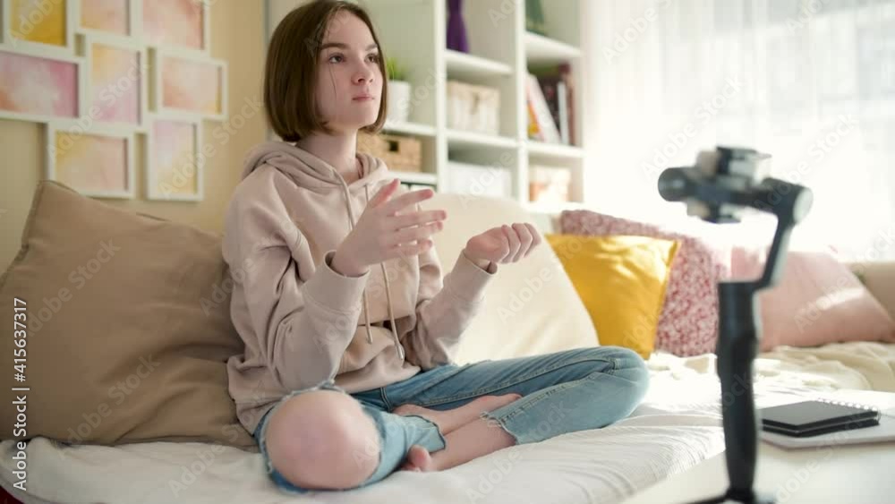 Beautiful teenage girl recording video blog with her smartphone. Young vlogger shooting vlog at home. Teen influencer creating content for her social media account. Social media and blogging concept.