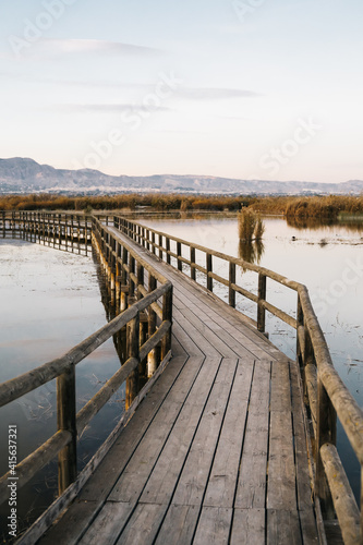 Wooden walkway over the water of the lake in the natural park "El Hondo" at sunset. Elche, Alicante, Spain.