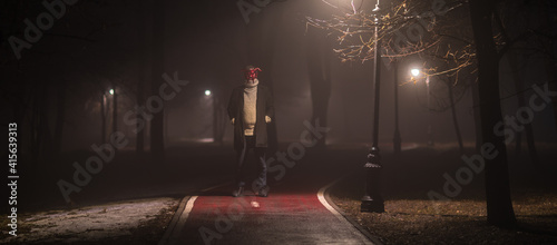 devil masked man in forest at night in fog