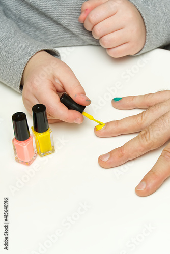 Girl paints her dad s nails with various colors. LGBT family concept