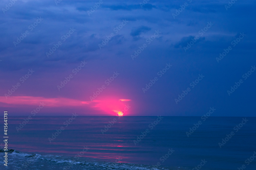 Fototapeta premium Colorful sunrise with sun on cloudy sea