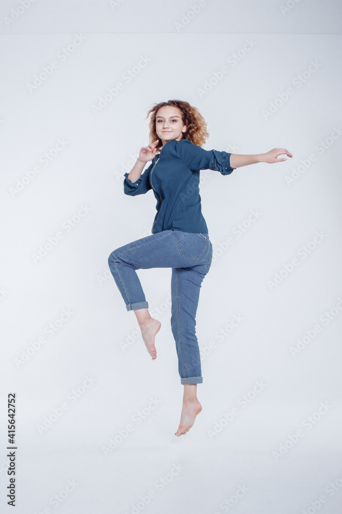 Funny european teenager curly hair girl dancing in studio. Portrait of cheerful fashion jumping hipster girl