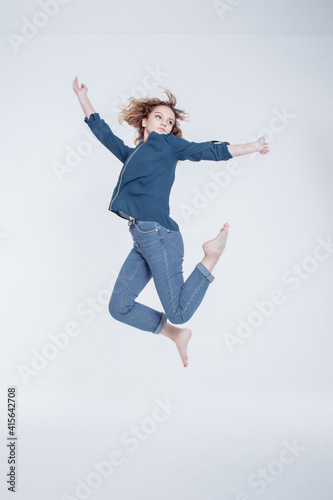 Funny european teenager curly hair girl dancing in studio. Portrait of cheerful fashion jumping hipster girl