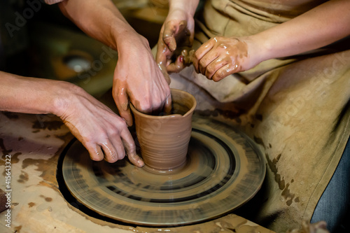 Pottery classes, student making clay pot on wheel. Close-up of dirty hands, sculpting clay crockery pottery training