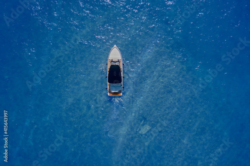 Yacht aerial view. Pleasure yacht in motion on blue transparent water top view. © Berg
