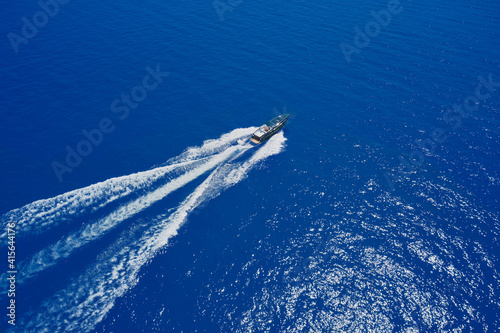 Speed boat at sea, view from above. High-speed yacht of blue color fast motion on blue water in the rays of the sun top view. © Berg