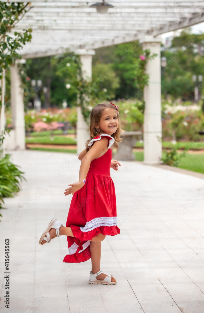 happy little girl in red dress posing in the park outdoors happy little girl in red dress posing in the park outdoors