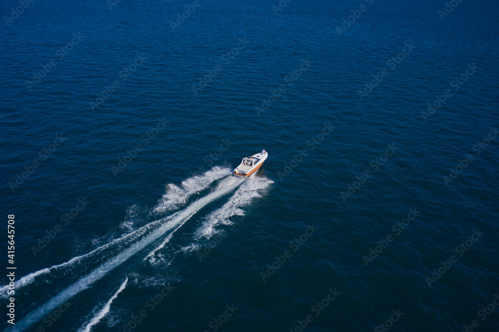 A boat with a motor on blue water. Top view of the boat. Aerial view luxury motor boat. Top view of a white boat sailing in the blue sea.