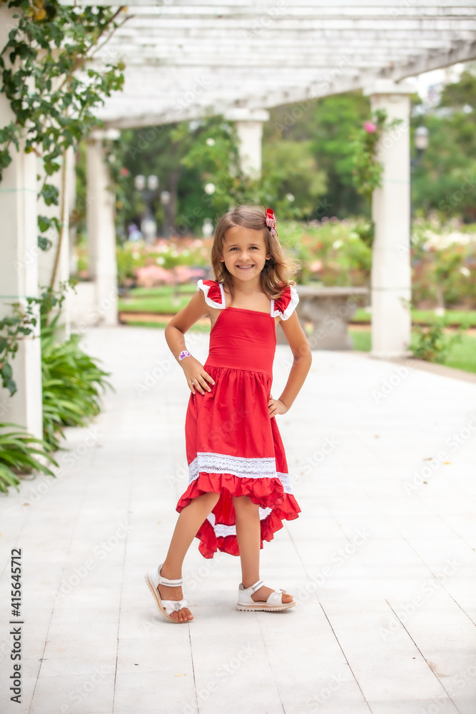 happy little girl in red dress posing in the park outdoors happy little girl in red dress posing in the park outdoors