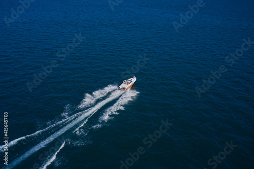 A boat with a motor on blue water. Top view of the boat. Aerial view luxury motor boat. Top view of a white boat sailing in the blue sea. © Berg