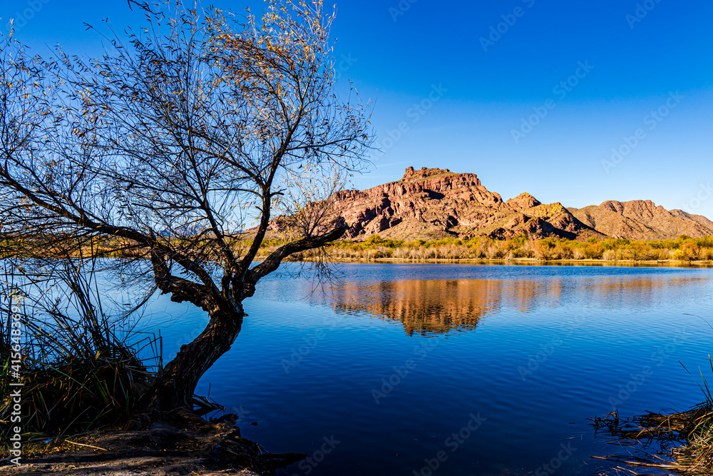 A red rock formation reflected in the blue waters of the Salt River in Arizona
