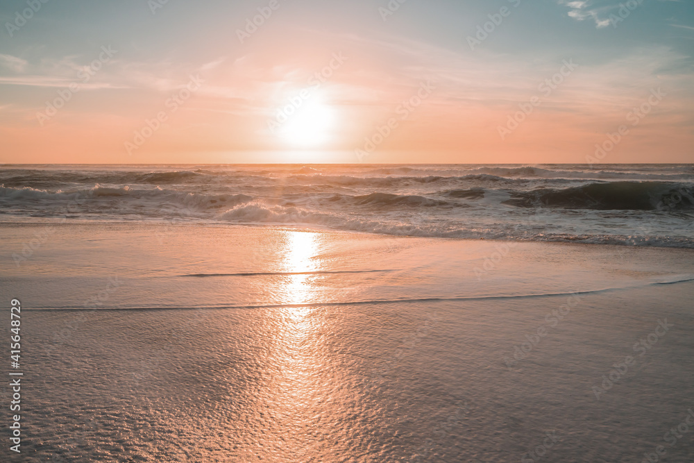 Sunset on the beach. Soft yellow-pink sunlight with beautiful sun reflections on golden sand