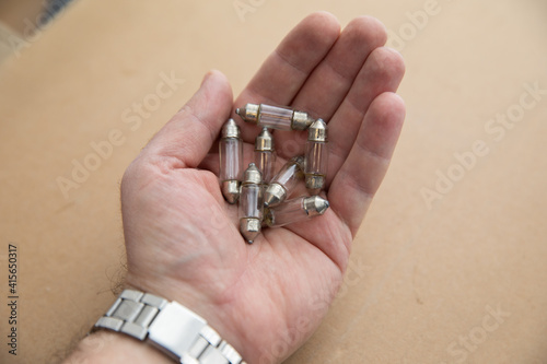 Old little incandescent light bulbs in the palm of a man's hand. Old radio components.