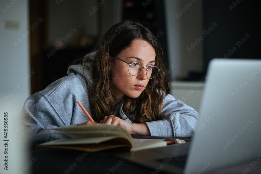Young millennial woman at home look at laptop and make notes in notebook. Learn new skill from online classes or masterclass. New generation use technology for education and freelance Young millennial woman at home look at laptop and make notes in notebook. Learn new skill from online classes or masterclass. New generation use technology for education and freelance