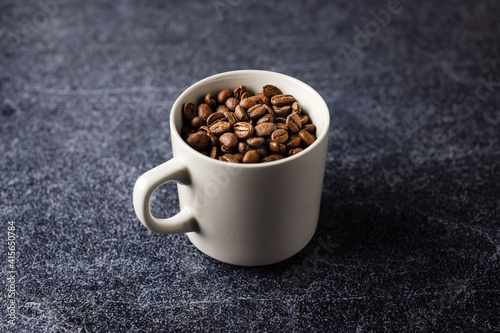 Coffee cup with coffee beans placed on a granite surface