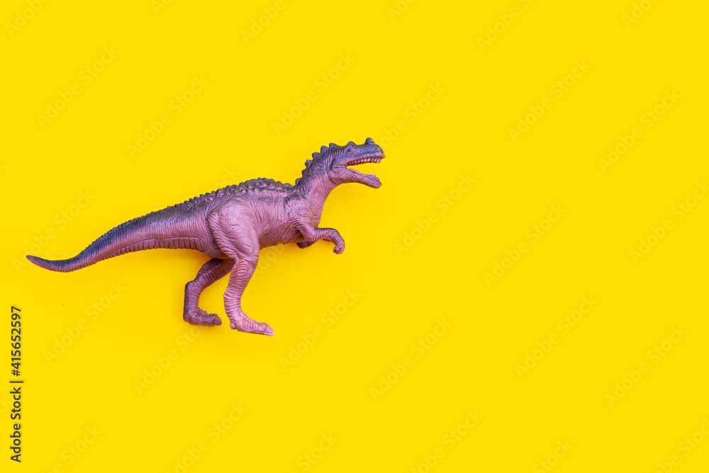 Fototapeta premium Plastic dinosaur toy on yellow background.