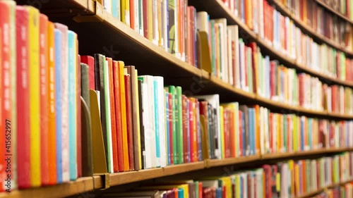 Camera moving along curved shelves with books in library