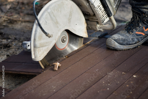 A worker cuts the wood with a petrol saw
