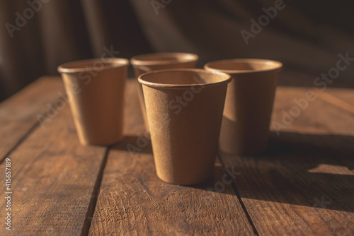 disposable dark brown kraft paper cups stand on wooden table