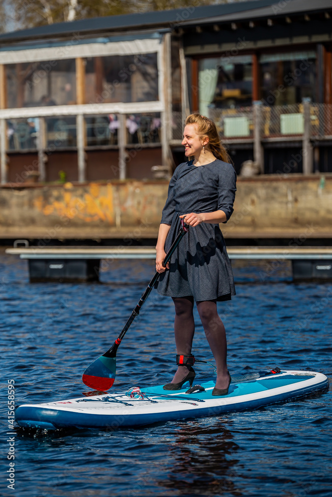 Business Woman in high heels paddling with SUP stand up paddle board