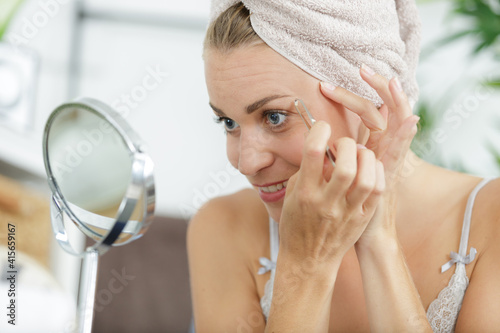 Obraz na plátně woman in cosmetics and facial care plugs her eyebrows