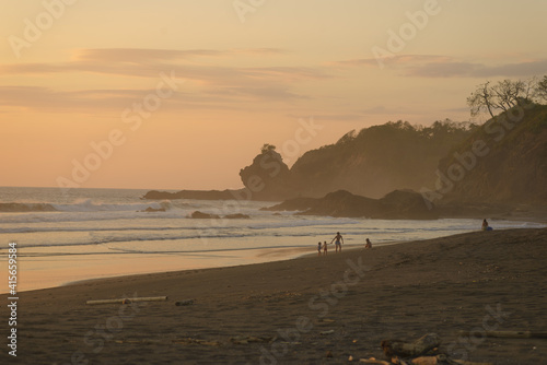 People palying on the beach during sunset