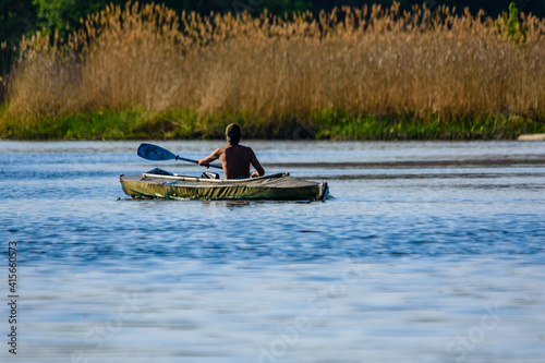 Young man kayaking on a river at summer