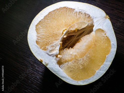 Cut in half the pomelo fruit on a dark background