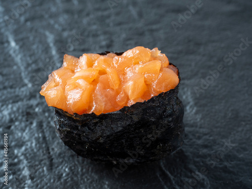 minced salmon guncan on a black textured surface. Close-up side view. Japanese cuisine photo