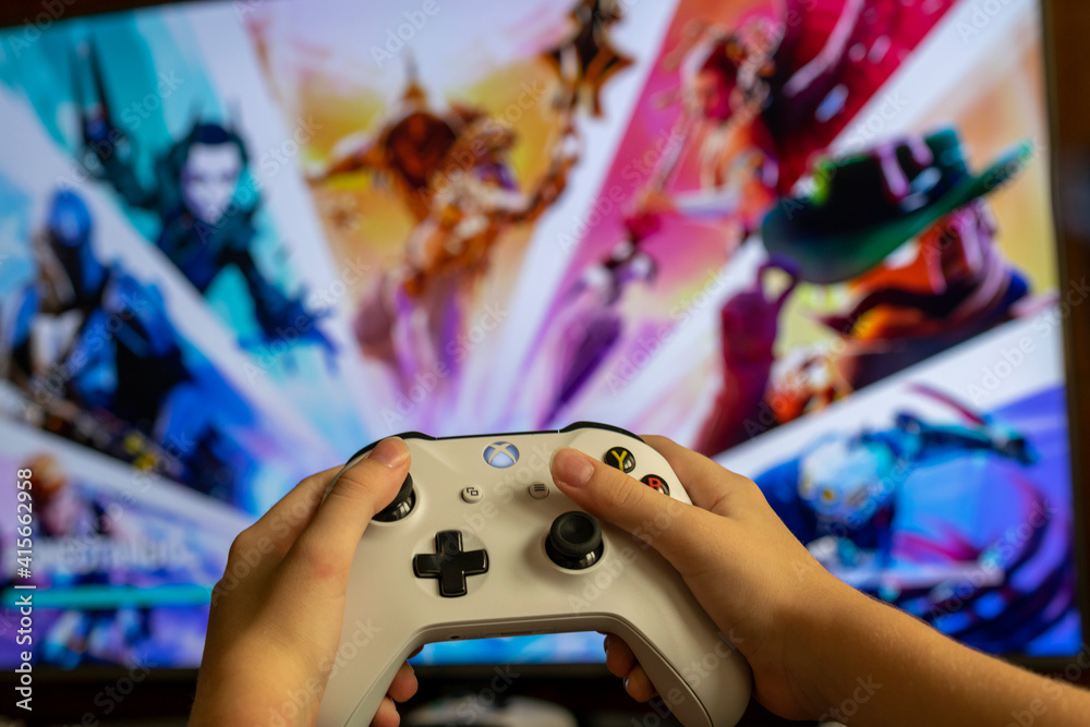 child with Xbox One video game controller, and in the background a blurred  television panel with a Fortnite game screen. Selective focus. Stock Photo  | Adobe Stock